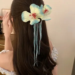 Floral hair clip with blue beaded tassels worn on long brown hair in a romantic style.