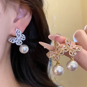 Élégantes boucles d'oreilles papillon avec perles blanches pendantes en finition argent et or