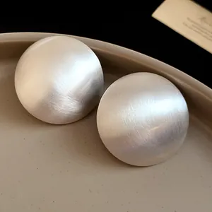 Detailed view of large brushed silver round stud earrings with premium texture