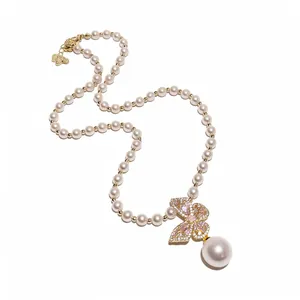 Collier de perles élégant avec pendentif papillon en cristal rose et grande perle goutte.