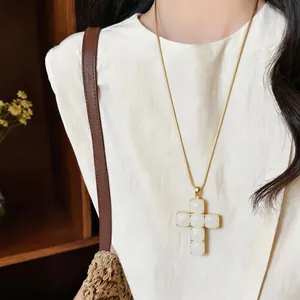 Detailed shot of white resin cross pendant on a gold snake chain necklace