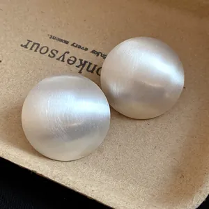 Detailed macro view showing the brushed matte texture of silver oversized round stud earrings