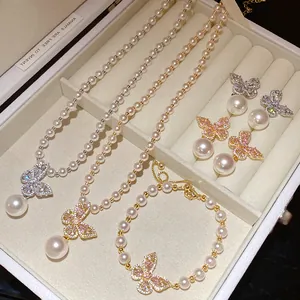 Parure de bijoux élégante en perles et papillons avec collier, bracelet et boucles d'oreilles.