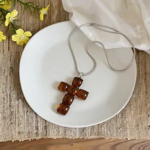 Detailed view of resin cross pendant necklace on white ceramic plate background