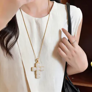 Elegant gold chain necklace featuring a large white resin cross pendant for women.