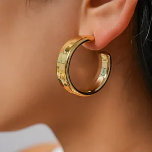 Detailed macro shot of a chunky polished gold-tone C-shaped hoop earring on ear