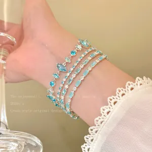 Close-up view of layered blue crystal bracelets on wrist with lace sleeve detail.