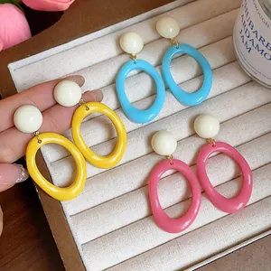 Close-up of colorful acrylic geometric oval drop earrings in a jewelry tray