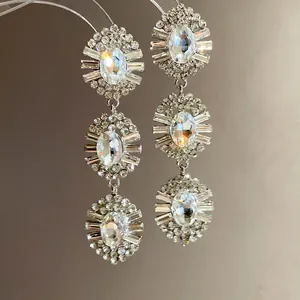 Elegant silver-tone chandelier earrings with oval crystals and rhinestone sunburst detail.