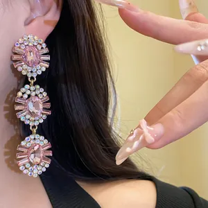 Close-up detail shot of pink oval tiered rhinestone tassel earrings worn on ear by model