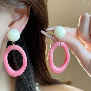 Close-up of trendy dopamine style acrylic geometric earrings in pink and white