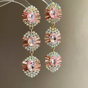 Close-up of elegant three-tier pink oval crystal earrings with sparkling rhinestones