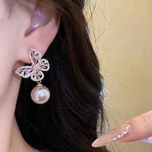 Gros plan d'une élégante boucle d'oreille papillon avec cristaux roses et perle à l'oreille