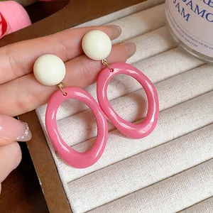 Close-up of pink and white acrylic geometric drop earrings on a jewelry tray