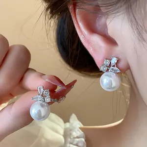 Close-up of elegant pearl stud earrings with sparkling cubic zirconia on model's ear