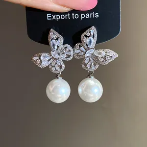 Gros plan de boucles d'oreilles papillon élégantes avec oxydes de zirconium et perles