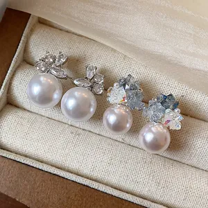 Detail of two styles of elegant pearl stud earrings with sparkling crystals in a box