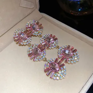Close-up detail of luxury pink rhinestone oval tassel earrings in a velvet box.
