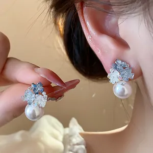 Close-up detail of sparkling zircon and pearl cluster earrings on ear