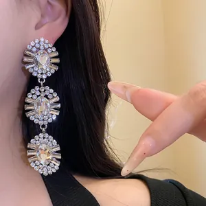 Close-up detail of vintage three-tier clear rhinestone drop earrings on model's ear