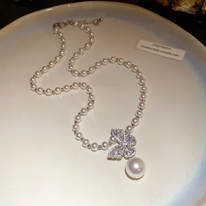 Détail d'un collier de perles élégant avec un pendentif papillon en cristal scintillant