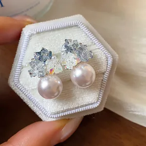 Close-up of elegant zircon and pearl stud earrings displayed on a white velvet jewelry box