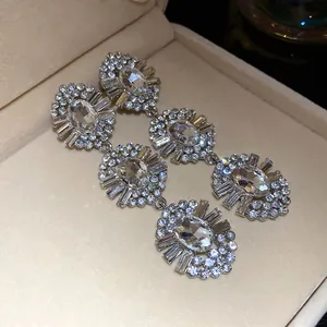 Detailed view of luxury oval rhinestone tassel earrings resting in a beige jewelry box