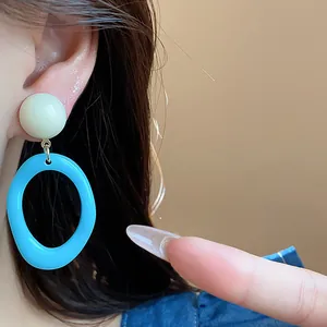 Close-up of summer dopamine acrylic drop earrings with cream and blue geometric design