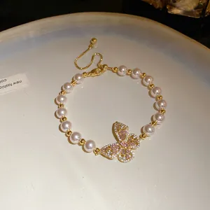 Vue détaillée du bracelet de perles élégant avec un pendentif papillon en cristal rose.