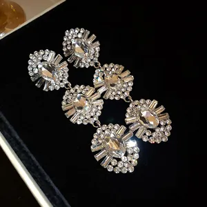 Detail view of shimmering oval rhinestone tassel earrings set on premium black velvet