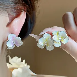 Detail shot of shimmering enamel flower stud earrings with a tiny zircon center.