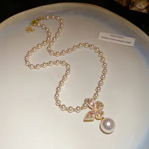 Vue détaillée d'un élégant collier pendentif papillon avec cristaux roses et perles blanches.