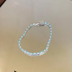 Detailed macro view of a tennis bracelet with blue and clear stones on a mirror