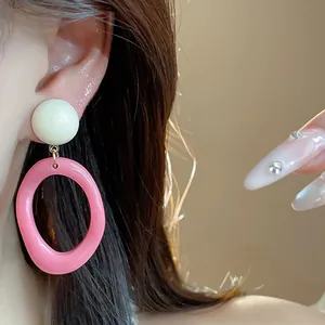 Close-up of vibrant pink and cream acrylic geometric drop earrings worn by a fashion model