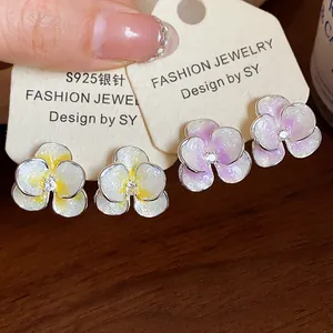 Detailed close-up of sparkling flower stud earrings with zircon center on display card