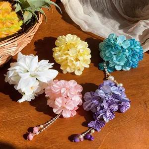 Detailed view of colorful fabric flower hair clips with elegant pearl tassel dangles