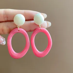 Close-up of pink and white acrylic geometric hoop earrings for summer fashion