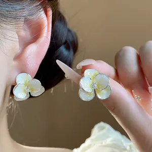 Detail shot of sparkling zircon flower stud earrings with shimmering oil-dripping texture.