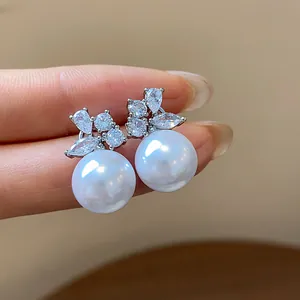 Detailed shot of elegant silver stud earrings with round pearls and sparkling zircons