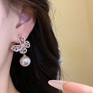 Gros plan de boucles d'oreilles papillon élégantes avec perles et cristaux roses sur modèle