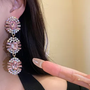 Close-up detail of luxurious pink rhinestone oval triple drop earrings worn on ear model