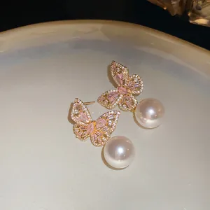 Détail rapproché de boucles d'oreilles papillon élégantes avec cristaux roses et perles blanches