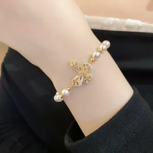 Détail d'un bracelet de perles de luxe avec un charmant papillon en zircon étincelant.