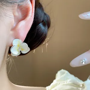 Close-up of a pearlescent white flower stud earring with a central zircon detail