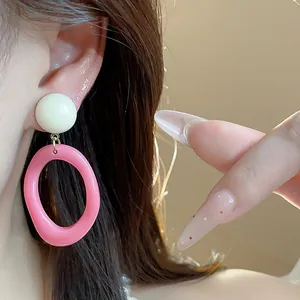 Close-up of summer dopamine acrylic earrings with pink oval hoop and white stud