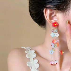 Detailed view of colorful resin flower tassel drop earrings worn by an Asian model
