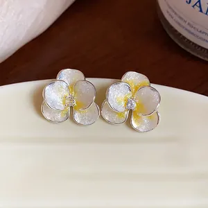 Detailed macro shot of elegant silver flower stud earrings with yellow drip oil and zircon