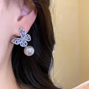 Boucle d'oreille papillon en cristal élégante avec perle pendante sur l'oreille du modèle