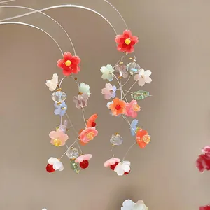 A close-up detailed shot of vibrant resin flower tassel earrings with transparent beads