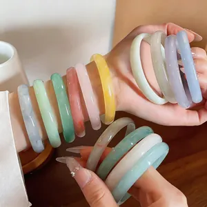 Macro detail of elegant multi-colored chalcedony bangles on a wrist with soft lighting